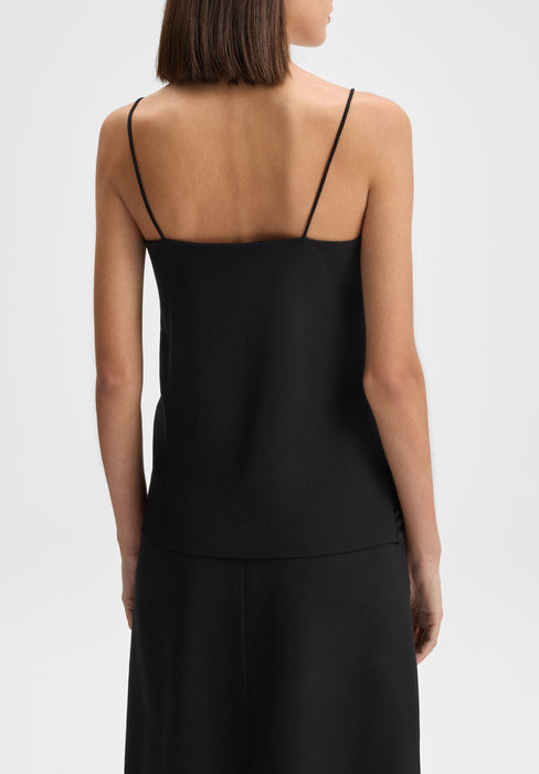 Back view close-up of a model from shoulders to hips wearing a black sleeveless top with thin spaghetti straps, standing upright with arms relaxed at her sides against a plain background.