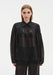 Front view of a model wearing a sheer black long-sleeve blouse with a pointed collar and gathered detailing, paired with matching translucent trousers, emphasizing the lightweight, semi-transparent fabric and relaxed silhouette.