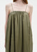 Close-up of an olive-green sleeveless dress with thin straps and a gathered neckline, highlighting the soft, lightweight fabric and loose, flowing drape.
