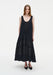 Front view of a model wearing a sleeveless black midi dress with a scoop neckline and a softly flared, semi-sheer panelled skirt, paired with black pointed shoes.