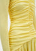 A close-up detail of a woman’s torso highlighting ruched fabric and gathered seams, with soft folds creating texture and movement against a plain background.