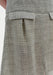 Close-up of a textured, light gray woven skirt featuring a subtle check pattern, with a structured waistband and a flap pocket detail at the hip.