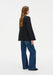 A woman with long light brown hair is shown in a three-quarter back pose against a plain background, standing with a relaxed posture and her head turned slightly to the side.