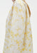 Close-up side view of a white long-sleeve top with a soft yellow floral pattern, highlighting the relaxed fit, smooth fabric, and subtle drape along the arm and shoulder.