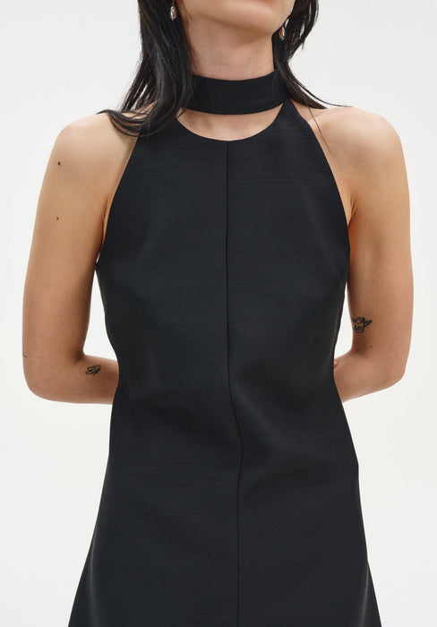 Close-up of a sleeveless black dress with a high choker-style neckline and clean, structured bodice.